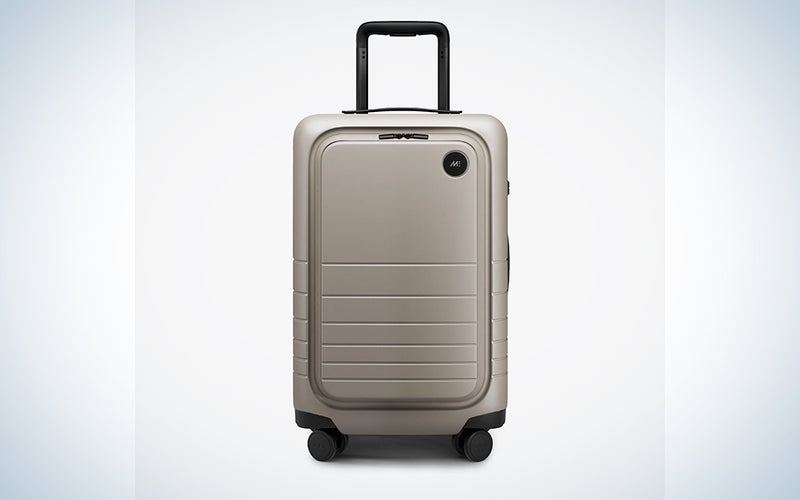 A beige Monos carry-on on a blue and white background
