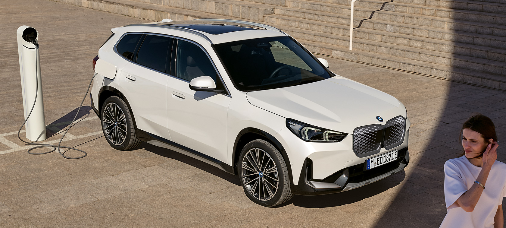 BMW iX1 U11 BEV side view charging BMW iX1 U11 BEV 2022 Mineral White metallic two third side view charging stairs