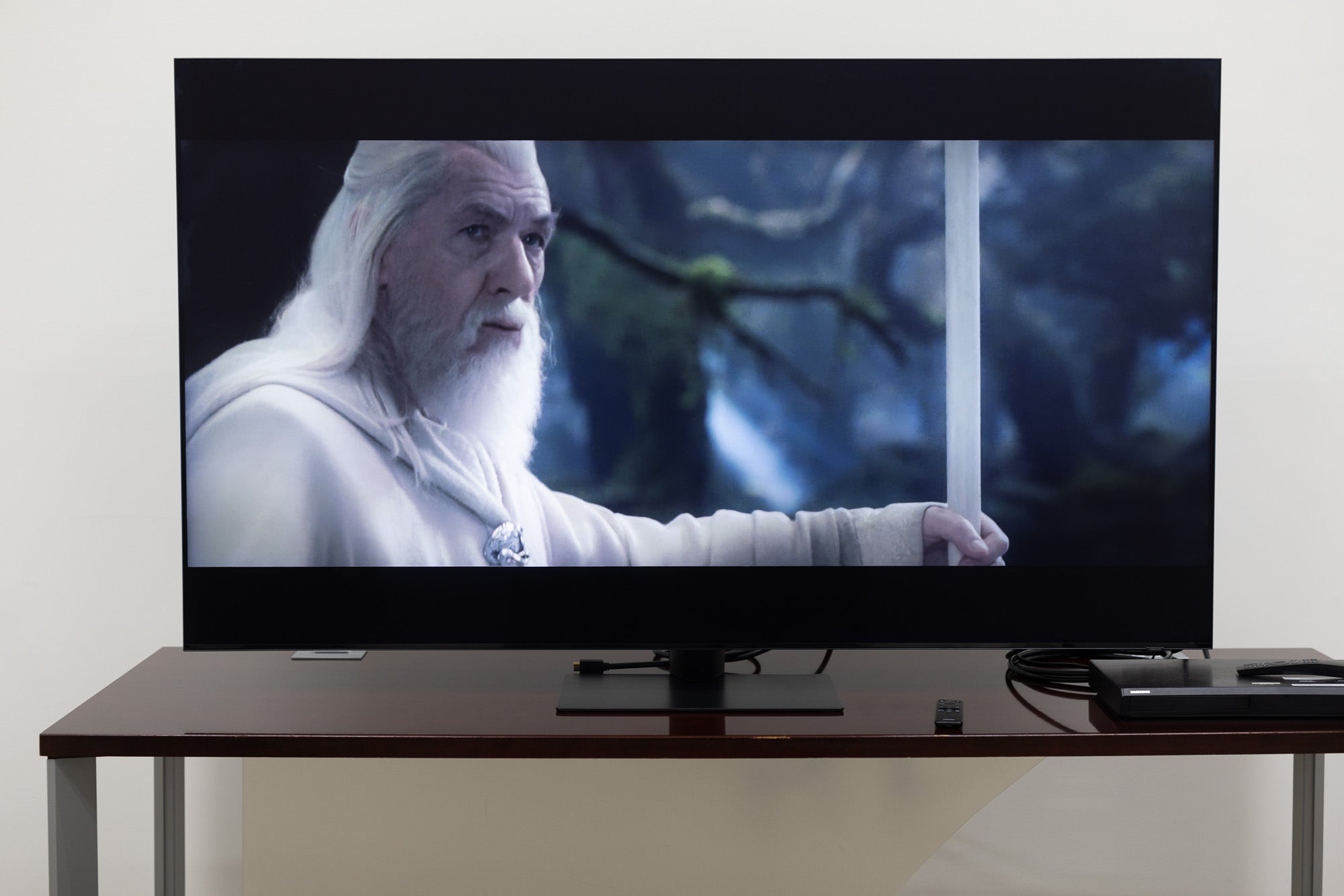 The Samsung QN90C TV on a stand in a room showing the Lord of the Rings.